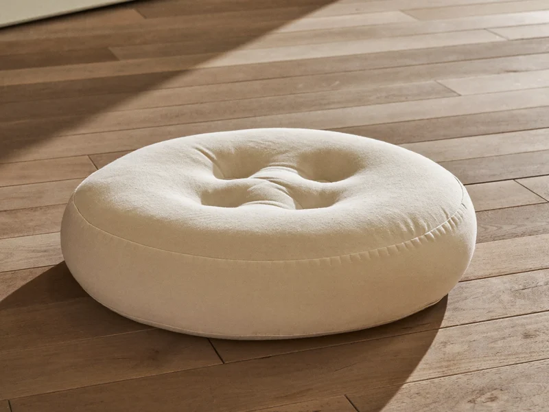 Coussin de méditation rond en coton écru posé sur un plancher en bois.